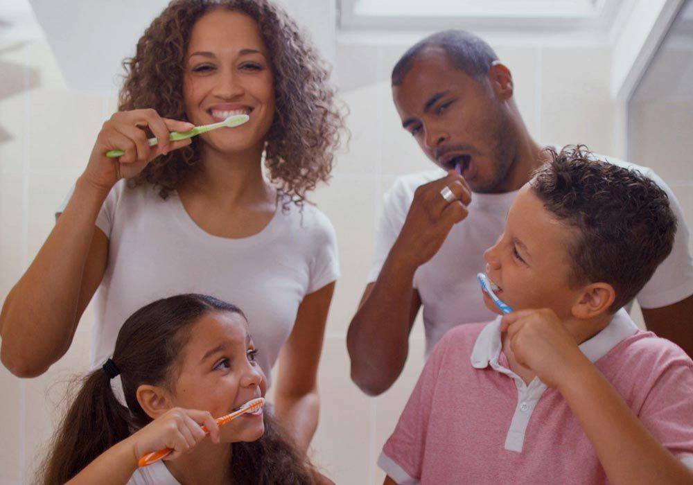 Parents brushing teeth with young girl and boy